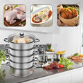 5-layer stainless steel steamer in modern kitchen with food, vegetables, and cooking utensils, showing cooked chicken, fish, and dumplings.