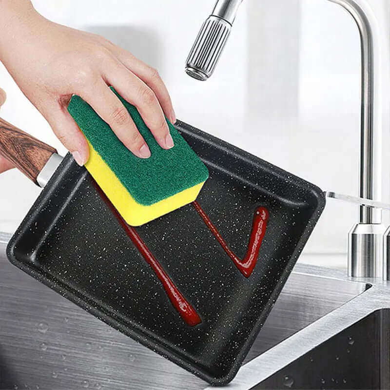 Cleaning a nonstick Tamagoyaki Japanese omelette pan under running water with a sponge.